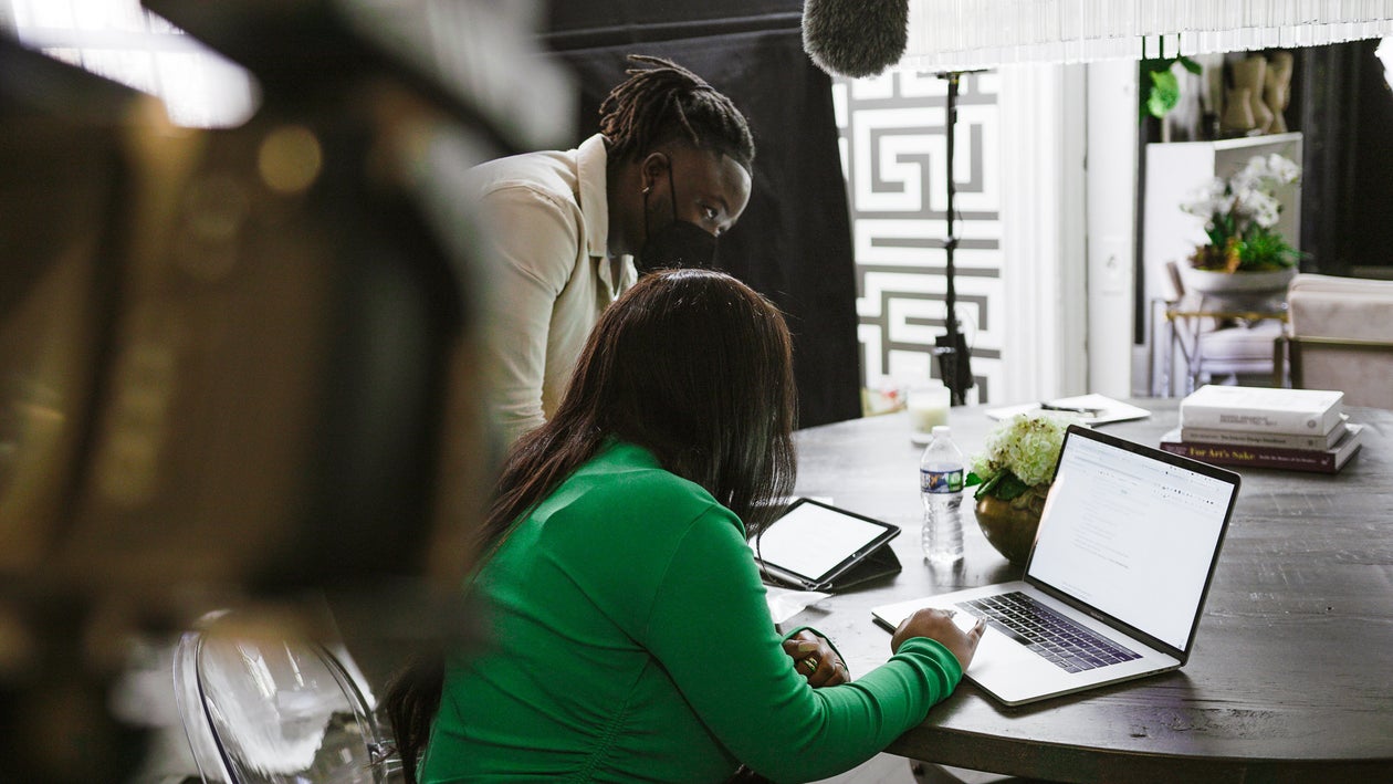 Two people working together at a laptop, one guiding the other through materials on screen